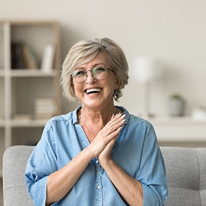 Senior woman with glasses smiling on couch at home