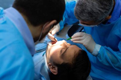 A dentist examines a patient's teeth during a routine dental check-up in a clinical setting.