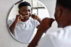 Man flossing his teeth in the mirror.